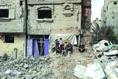 Palestinians sit amid debris following overnight Israeli bombardment in Rafah Wednesday.