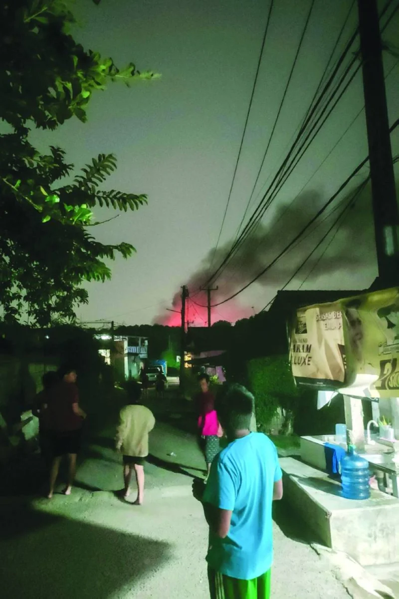 People watch a fire in the distance from a street in Bogor, West Java. Multiple explosions ripped through a military ammunition warehouse on the outskirts of the Indonesian capital Jakarta, the army said, with no casualties immediately reported.