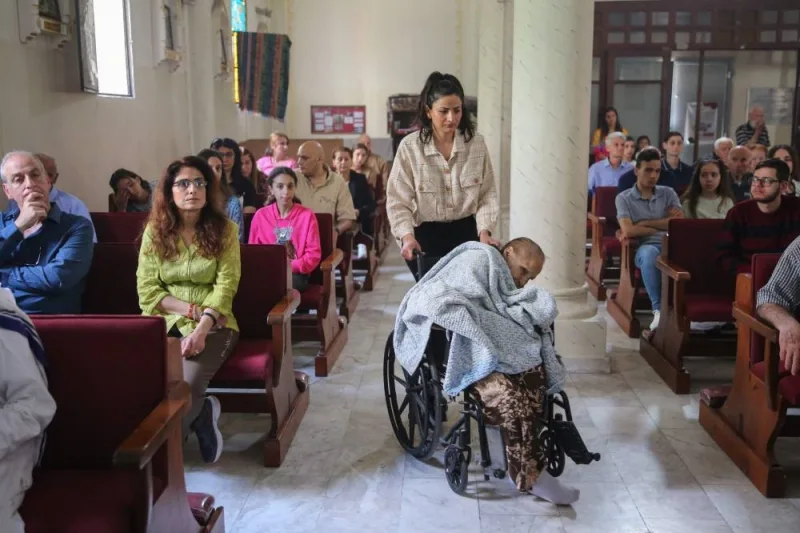 A woman pushes an elderly worshipper in a wheelchair as Palestinian Christians celebrating Easter Sunday Mass at the Catholic Holy Family Church in Gaza City, on Sunday. AFP