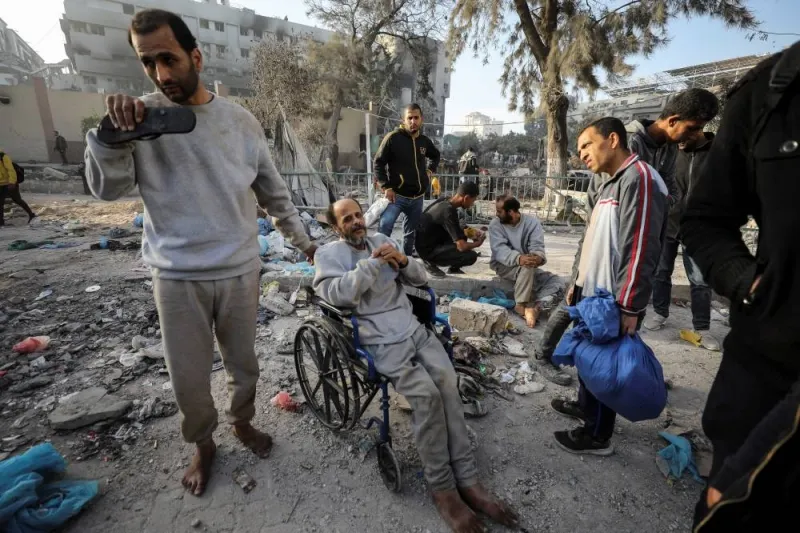 A man sits in a wheelchair as Palestinians inspect the damages at Al Shifa Hospital after Israeli forces withdrew from the hospital and the area around it. REUTERS