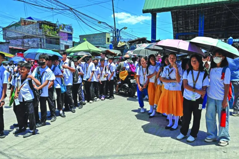 
Students use umbrellas to protect themselves from the sun as they line up to wait for their classes outside their school in Manila yesterday. 