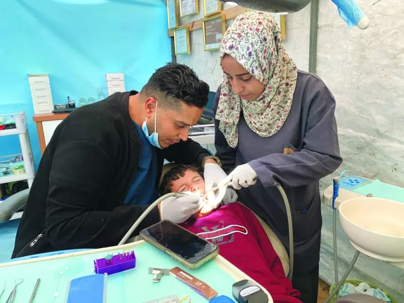 
Palestinian dentist Najdat Saqr, whose clinic was destroyed during an Israeli bombardment, treats patient at a tent he set up, amid the ongoing conflict between Israel and Hamas, in Nuseirat camp in the central Gaza Strip. 