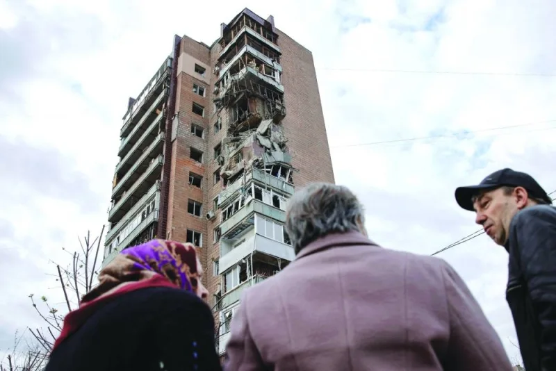 
Local residents stand in front of an apartment building hit by a Russian drone strike in Kharkiv. 
