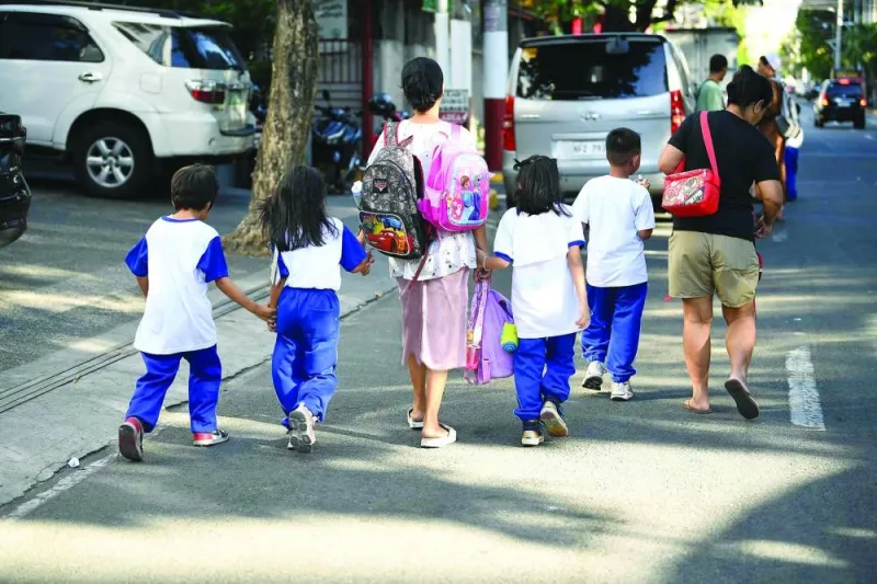 Parents accompany children from school after classes in Manila on Friday. Thousands of schools in the Philippines suspended in-person classes on Friday, the education department said, as parts of the tropical country endured dangerously high temperatures.