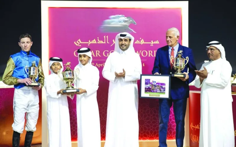 
HE Sheikh Abdullah bin Tamim bin Hamad al-Thani and HE Sheikh Al Qaqa bin Tamim bin Hamad al-Thani receive the Qatar Gold Trophy from QREC Chairman Issa bin Mohamed al-Mohannadi following the victory of Wathnan Racing’s Bolthole in the QA Gr1 race for Thoroughbreds. 