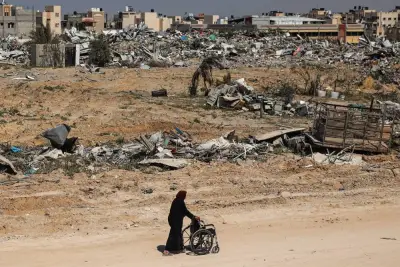 A Palestinian elderly woman pushes a wheelchair past rubble in Khan Yunis Sunday after Israel pulled troops out of the southern Gaza Strip.