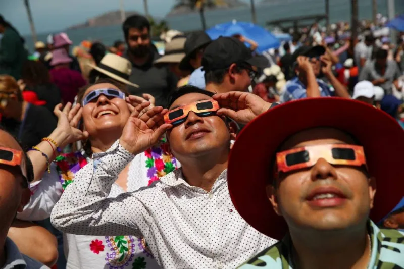 People use special protective glasses to observe a total solar eclipse in Mazatlan, Mexico, Monday. REUTERS