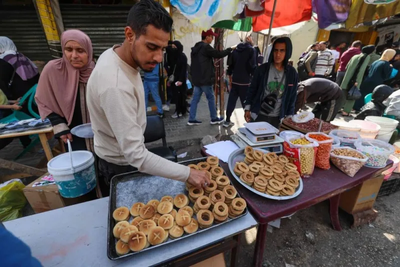 A Palestinian confectioner sorts traditional cookies on a street stall ahead of Eid al-Fitr, in Rafah in the southern Gaza Strip Monday.