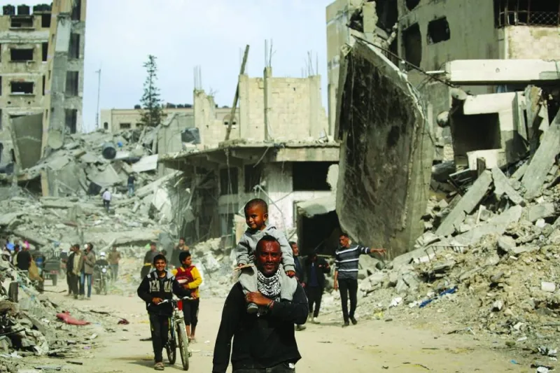 Palestinians walk past damaged buildings in Khan Yunis, yesterday, after Israel pulled its ground forces out of the southern Gaza Strip, six months into the devastating war.
