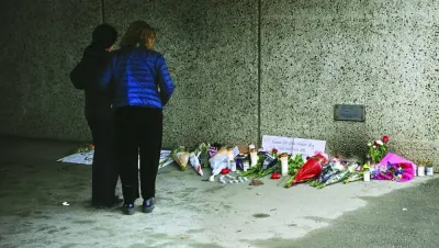 People stand at a makeshift memorial near the centre of Skaerholmen, south of Stockholm, where a father was shot dead in an underpass earlier this week.
