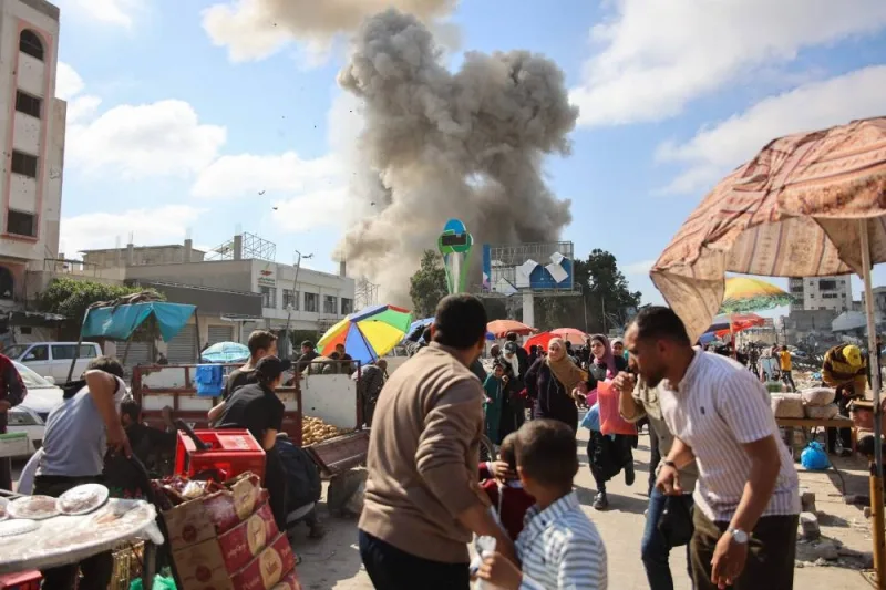Palestinians look at smoke billowing during Israeli bombardment on the Firas market area in Gaza City on Thursday. AFP
