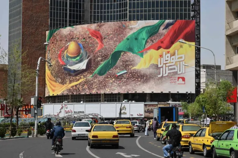 Iranians drive in down a street next to a pro-Palestine poster in Tehran on Saturday. AFP