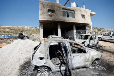 A Palestinian man sits near a damaged house and damaged cars after Israeli settlers attacked the village of al-Mughayyer, in the Israeli-occupied West Bank, on Saturday. REUTERS