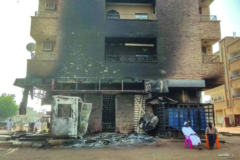 File photo shows men sitting outside a burnt-down bank branch in southern Khartoum, amid the ongoing conflict in Sudan between the army and paramilitaries.
