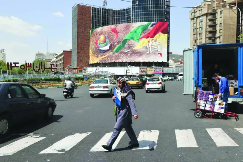
An Iranian crosses the road next to a pro-Palestine poster in Tehran. 