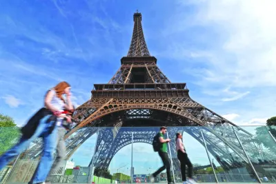 
Pedestrians walk past the Eiffel Tower in Paris. 