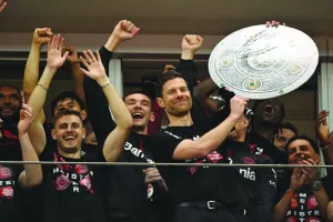 Bayer Leverkusen’s coach Xabi Alonso celebrates with a mock-up of the Bundesliga trophy with his players after the match against Werder Bremen in Leverkusen, Germany, yesterday. (AFP)