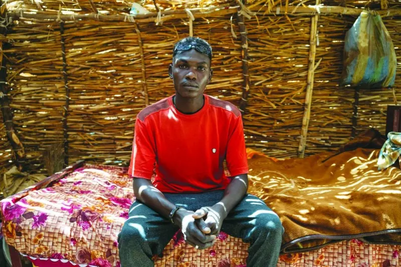 
File photo shows Sudanese refugees standing at the entrance of a health centre in the Koufroun refugee camp. Below: File photo shows 24-year-old Sudanese refugee Alabaki Abbas Ishag posing inside his shelter in the Koufroun refugee camp. 