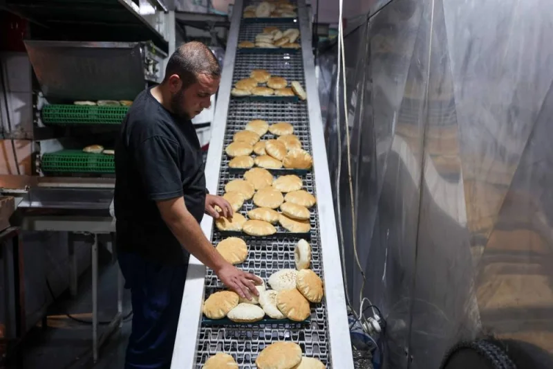A Palestinian worker arranges freshly baked flatbread at a bakery in Gaza City on Sunday. AFP