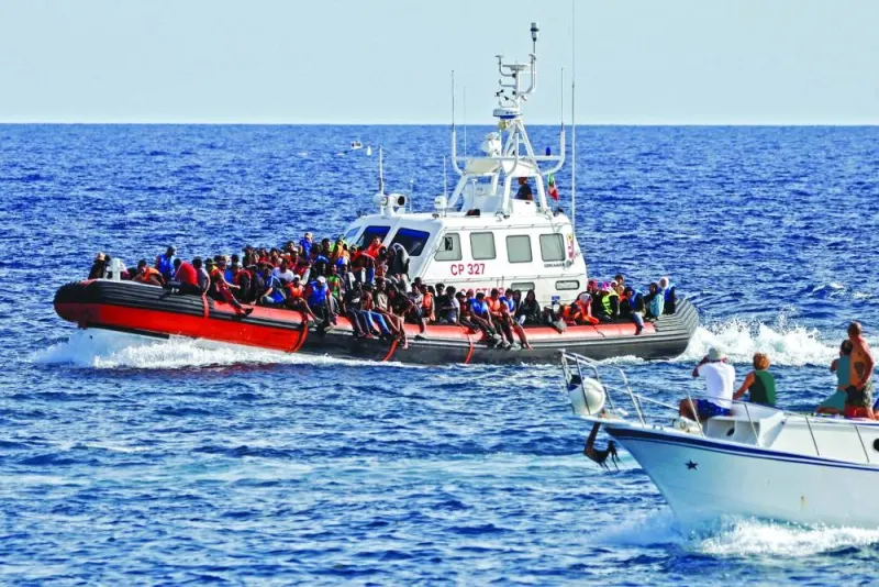 
This picture taken last year shows an Italian Coast Guard vessel carrying migrants rescued at sea passes near a tourist boat, on the Sicilian island of Lampedusa. 