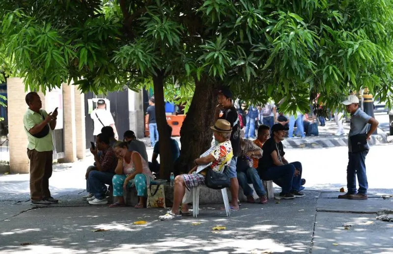 People take shelter under a tree along a road in Manila Wednesday, as extreme heat affected the country. AFP
