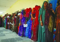 Women stand in a queue to cast their vote at a polling station during the second phase of the general elections, in Barmer, Rajasthan, 
on Friday.