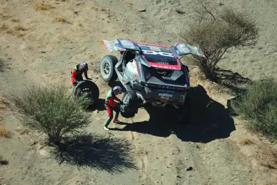 Qatari driver Nasser al-Attiyah and his co-driver Edouard Boulanger repair their car after a puncture during Stage 2B of the 47th Dakar Rally in Bisha, Saudi Arabia, on Monday. (AFP) Qatari driver Nasser al-Attiyah and his co-driver Edouard Boulanger repair their car after a puncture during Stage 2B of the 47th Dakar Rally in Bisha, Saudi Arabia, on Monday. (AFP)