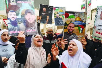 Palestinians hold placards as they protest condemning Israeli bombardment on Gaza, in Nablus, in the occupied West Bank, yesterday. Palestinians hold placards as they protest condemning Israeli bombardment on Gaza, in Nablus, in the occupied West Bank, yesterday.