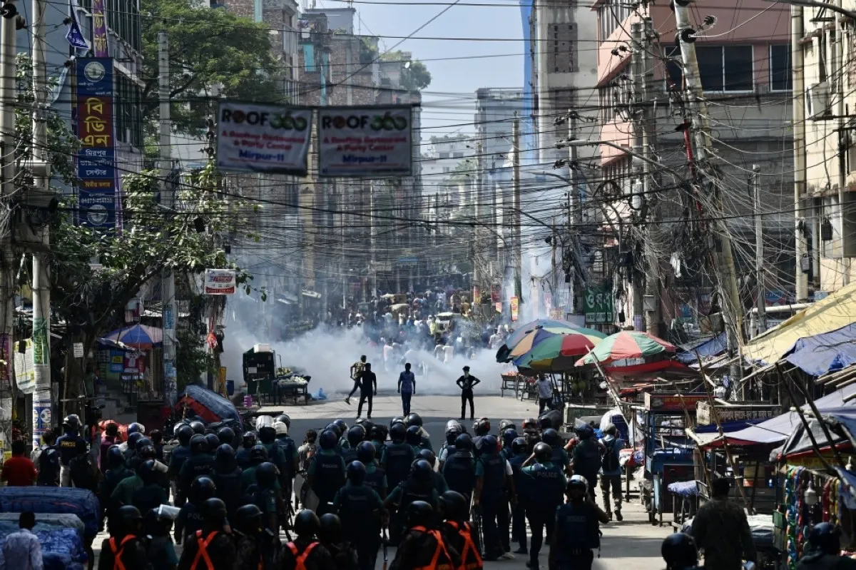DHAKA: Bangladesh police (foreground) stand guard along a road during clashes with garment workers (top) protesting to demand the increase of their salaries, in Dhaka. – AFP