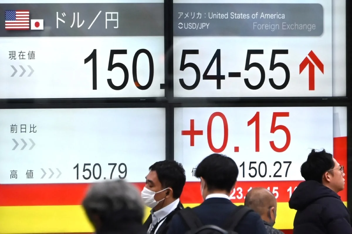TOKYO: Pedestrians walk past an electronic board showing the rate of the Japanese yen versus the US dollar along a street in Tokyo on November 15, 2023. – AFP