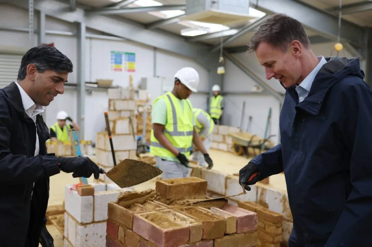 LONDON: Britain’s Prime Minister Rishi Sunak (left) and Britain's Chancellor of the Exchequer Jeremy Hunt learn how to lay bricks during a visit to a college in north London on November 20, 2023. –AFP