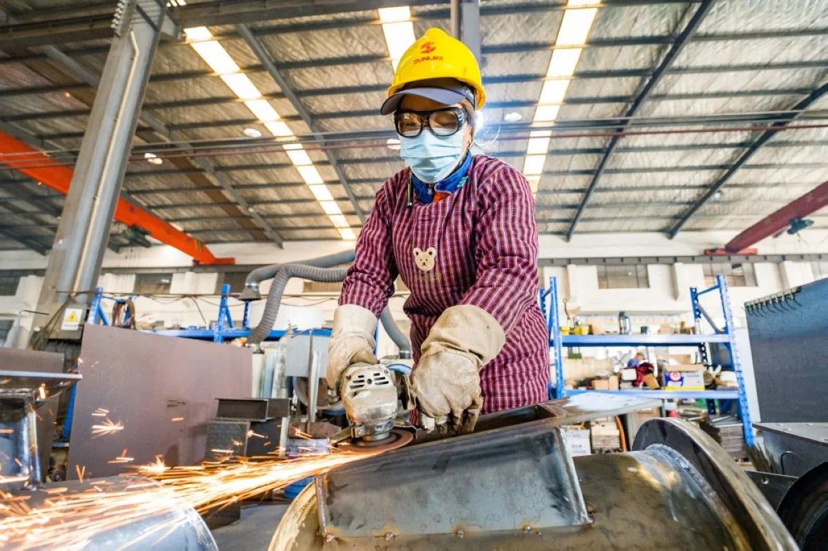 An employee produces building material processing equipment at a factory in Nantong, in China's eastern Jiangsu province on December 5, 2023. -- AFP