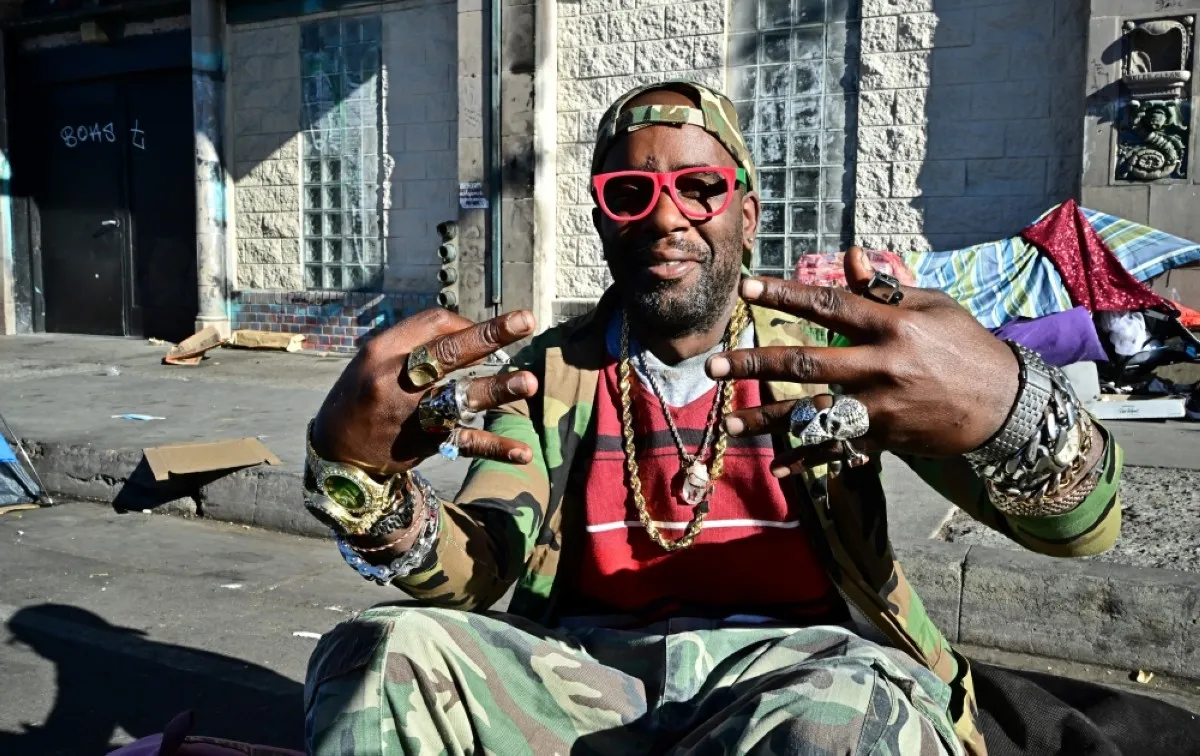 LOS ANGELES: A homeless man gestures while sitting on a luggage bag along a downtown Los Angeles street lined with tents housing the homeless on November 22, 2023 in Los Angeles, California. – AFP