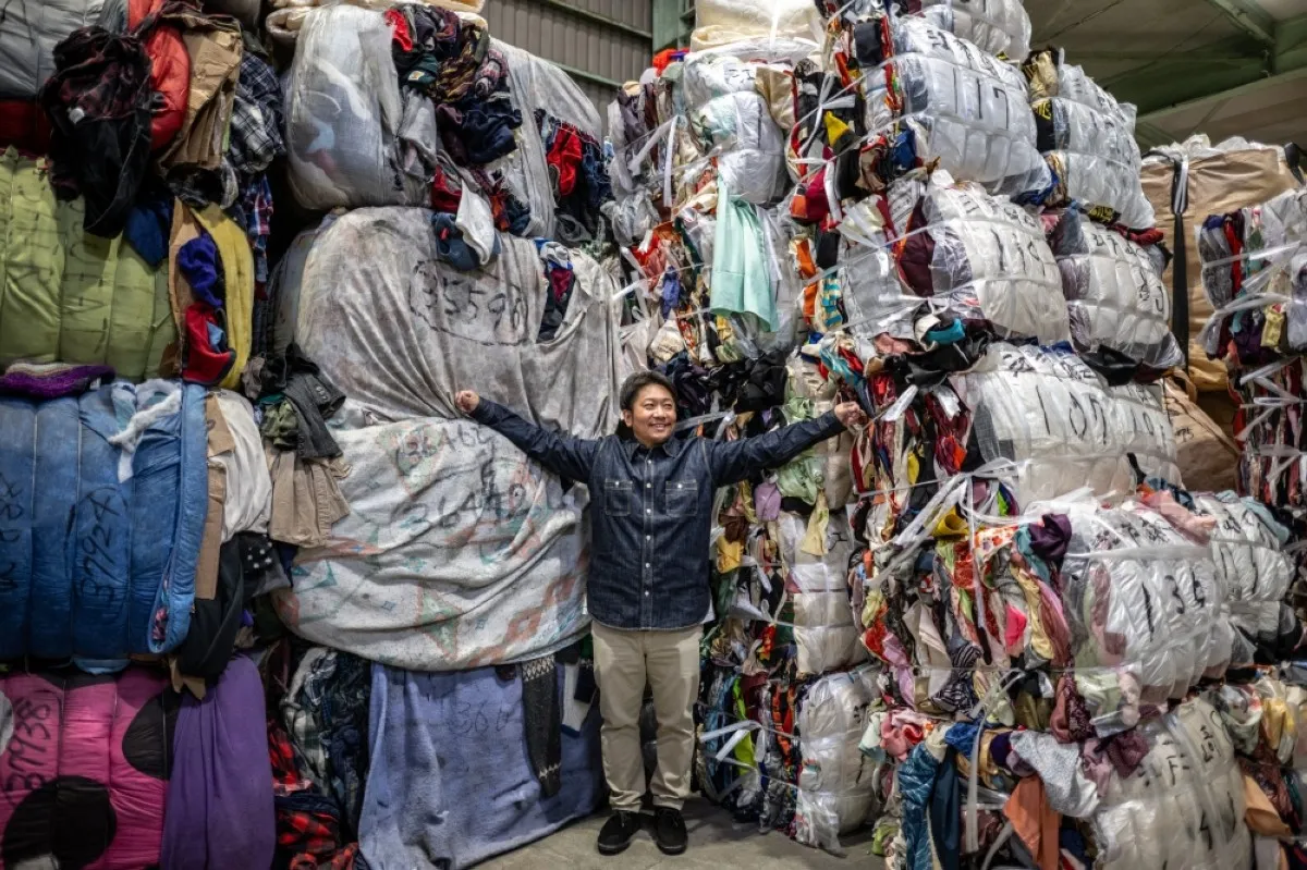 INASHIKI, Japan: This picture taken on October 31, 2023 shows logistics manager Osamu Ubakai posing with bundles of secondhand clothes at a warehouse in Inashiki city, Ibaraki Prefecture. -- AFP