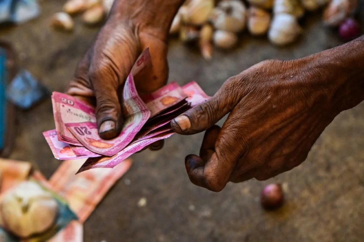 COLOMBO: A vendor holds Sri Lankan bank notes while working at a market in Colombo. – AFP