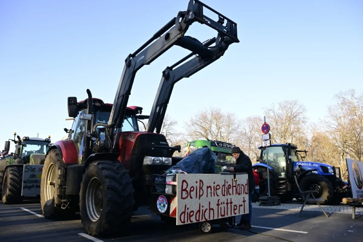 BERLIN: A placard reading ‘Don’t bite the hand that feeds you’ is attached on a tractor parked at the “Strasse des 17 Juni” boulevard, towards the Brandenburg Gate in Berlin.- AFP