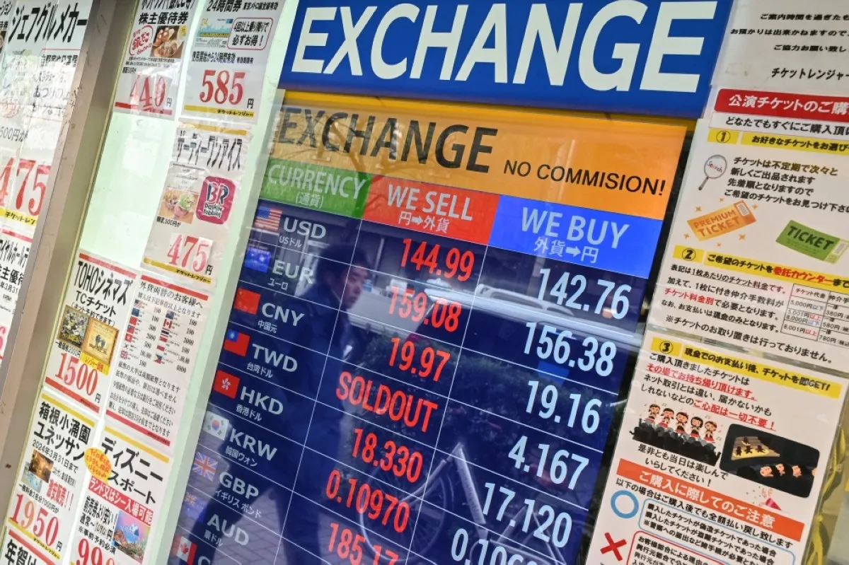 TOKYO: A passing pedestrian is reflected in the glass of a shop advertising foreign currency exchange rates in downtown Tokyo on January 16, 2024. – AFP