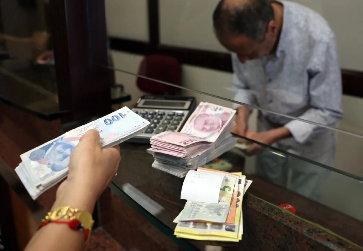 ANKARA: A customer buys US dollars in exchange for Turkish lira at an exchange office in Ankara.- AFP