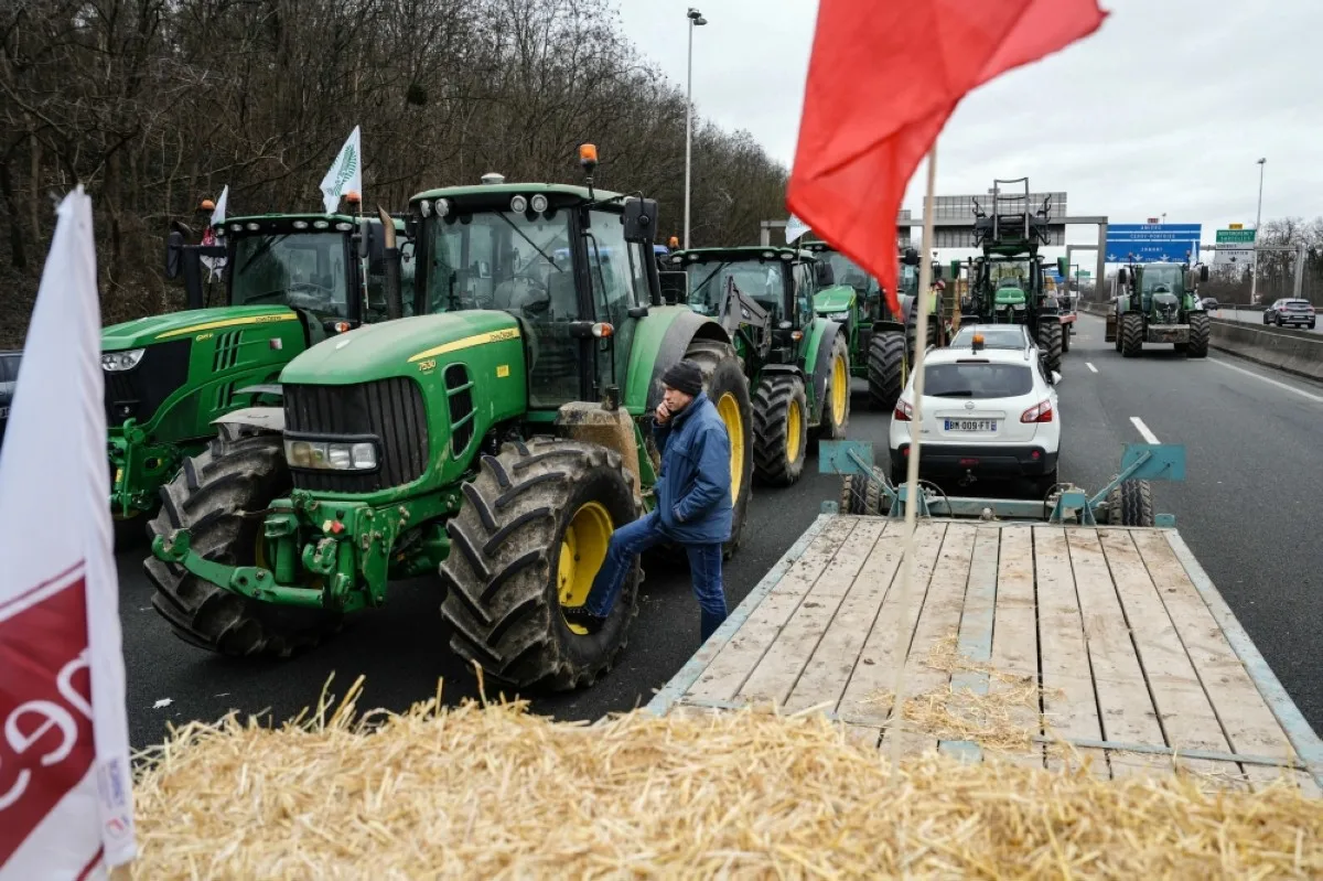 ARGENTEUIL, France: A protester stands next to tractors blocking the A15 highway near Argenteuil, northwest of Paris, as French farmers maintain roadblocks on key highways into Paris for a second day, as part of nationwide protests called by several farmers' unions over pay, tax and regulations. -- AFP