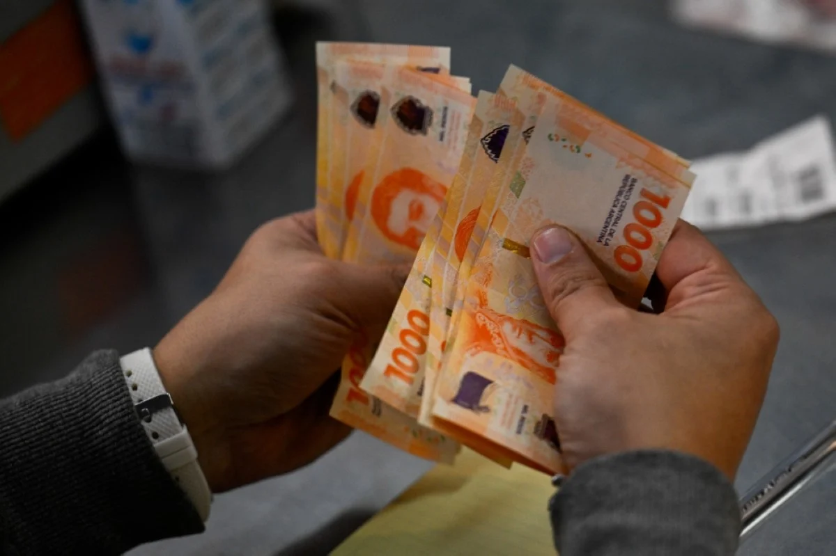 BUENOS AIRES: A man counts one thousand Argentinean peso banknotes in Buenos Aires. – AFP