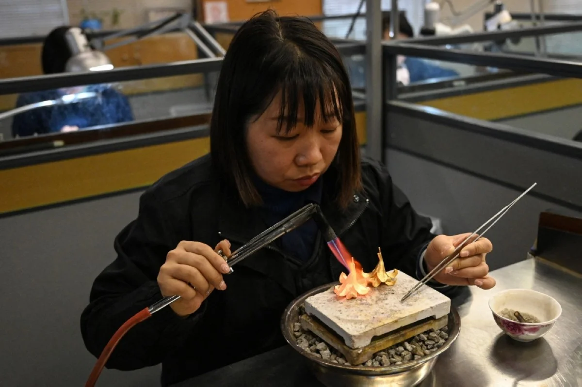 FOSHAN, China: This photo taken on Jan 26, 2024 shows a jewelry craftswoman heating a gold flower to shape the petals at a master studio in Foshan, in southern China's Guangdong province. -- AFP