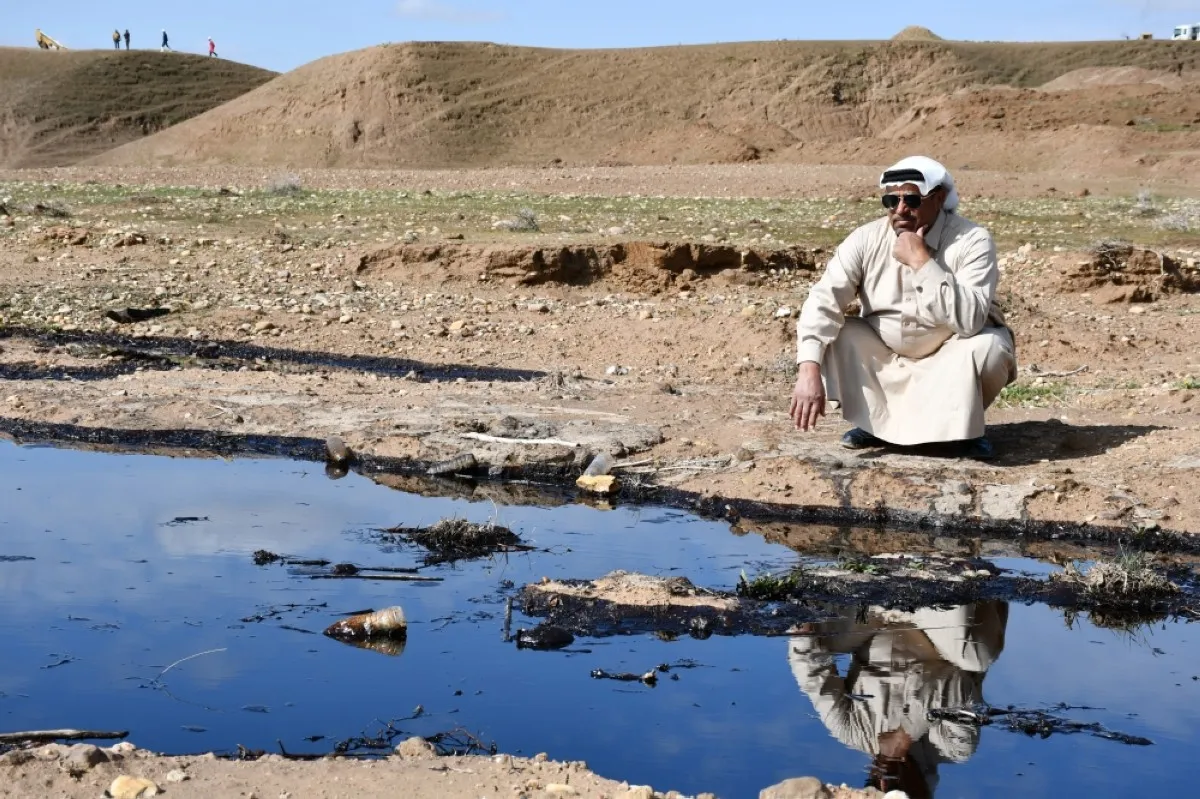 NAHIYAH, Iraq: An Iraqi farmer squats and checks an oil spill into an agricultural land in the region of Hamrin, north of Tikrit, in the province of Salaheddin. – AFP