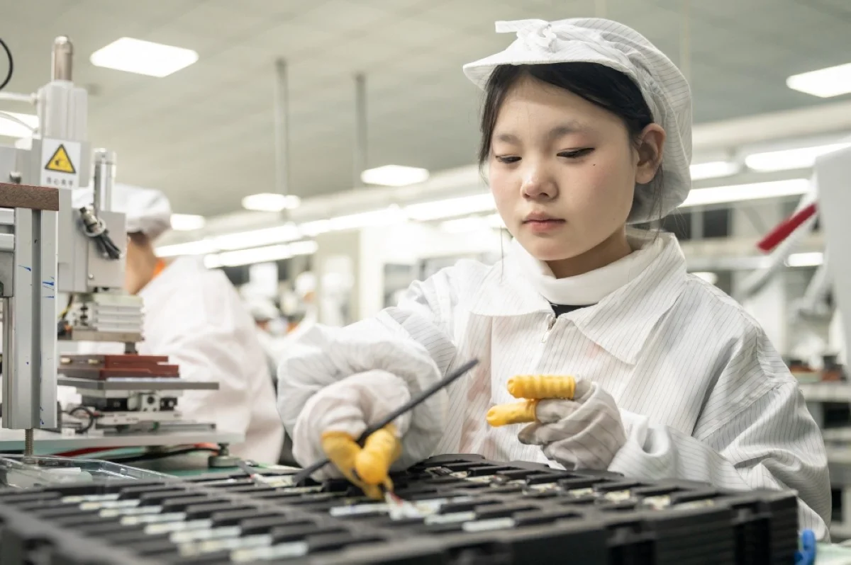 NANTONG, China: Employees work on a production line at a workshop for Celxpert Energy Corporation, which makes lithium batteries for laptops and other uses, in Nantong in China's eastern Jiangsu province. – AFP