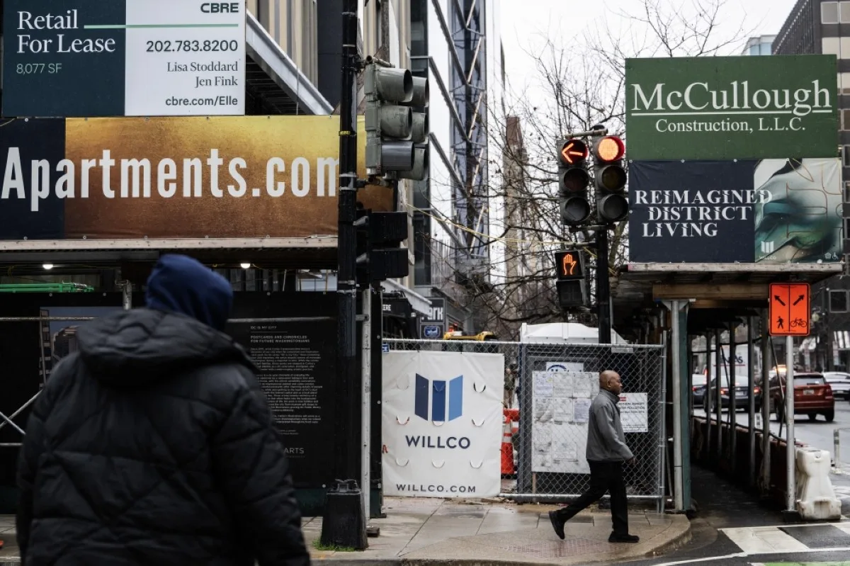 WASHINGTON: People walk past a former office building being converted into apartments in Washington, DC. – AFP