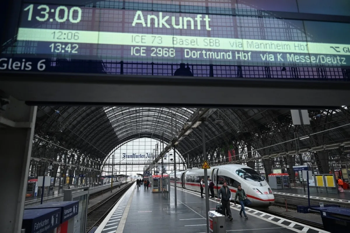 FRANKFURT: Commuters walk along the platform past an ICE train during a train drivers strike at Frankfurt's main train station. -- AFP
