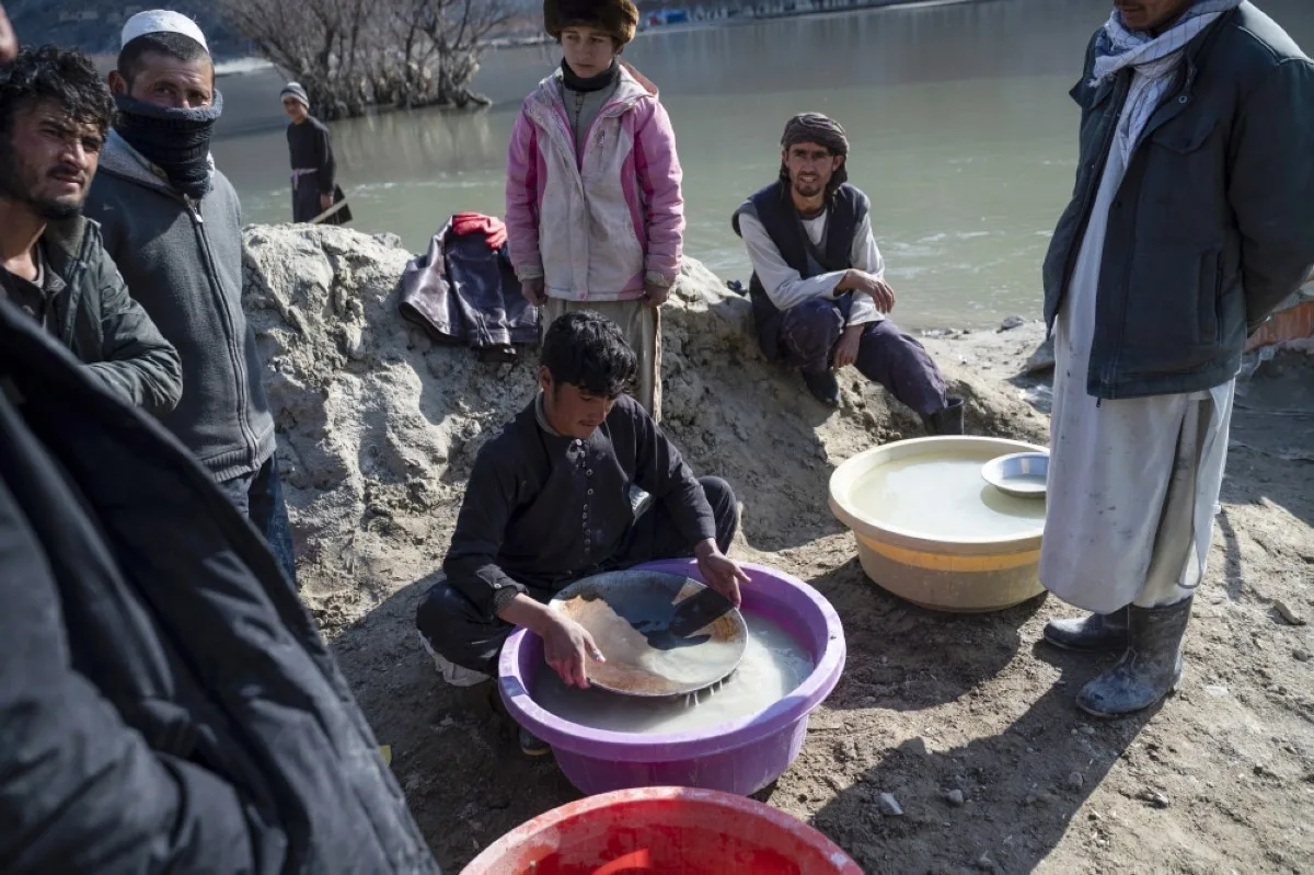 YAFTAL SUFLA, Afghanistan: In this photograph taken on February 24, 2024, an Afghan youth (center) pans for gold in a traditional way at a gold mine along the Kokcha River at Yaftal Sufla district in Badakhshan province.-- AFP