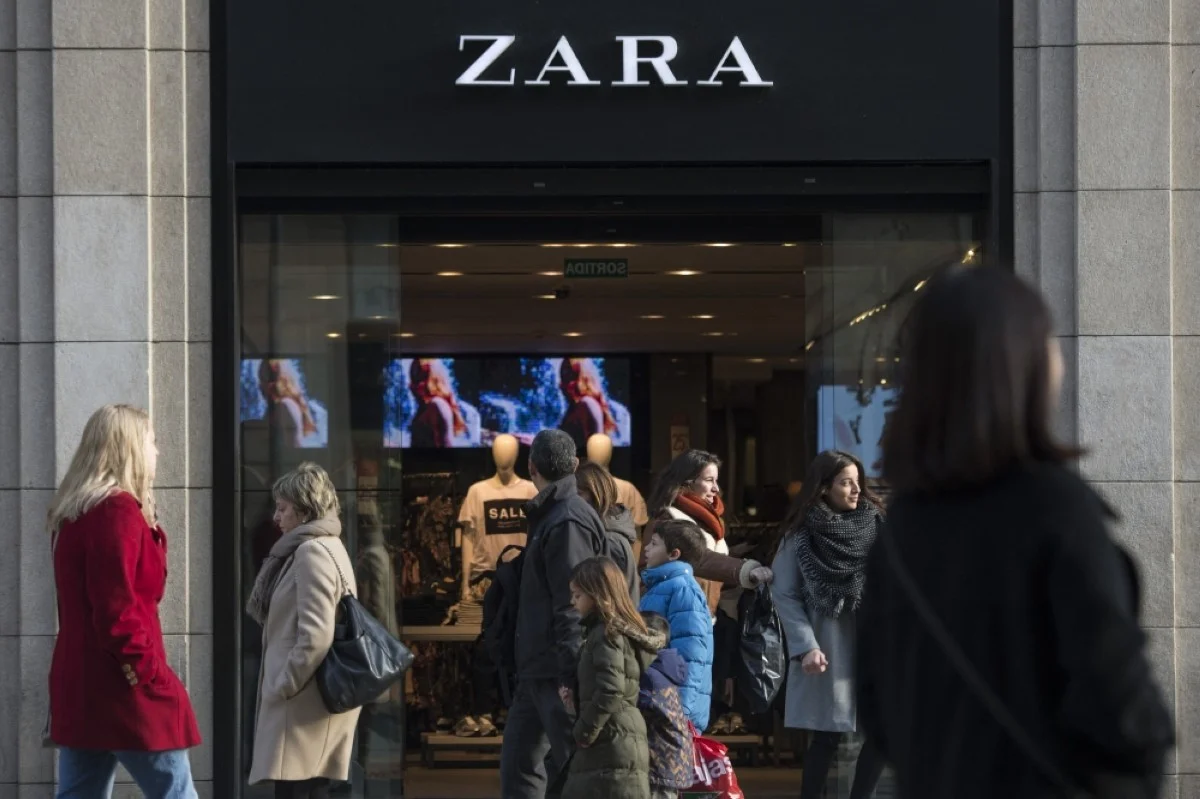 BARCELONA: People pass by a Zara shop announcing discounts on the first day of the winter sales in Barcelona. -- AFP