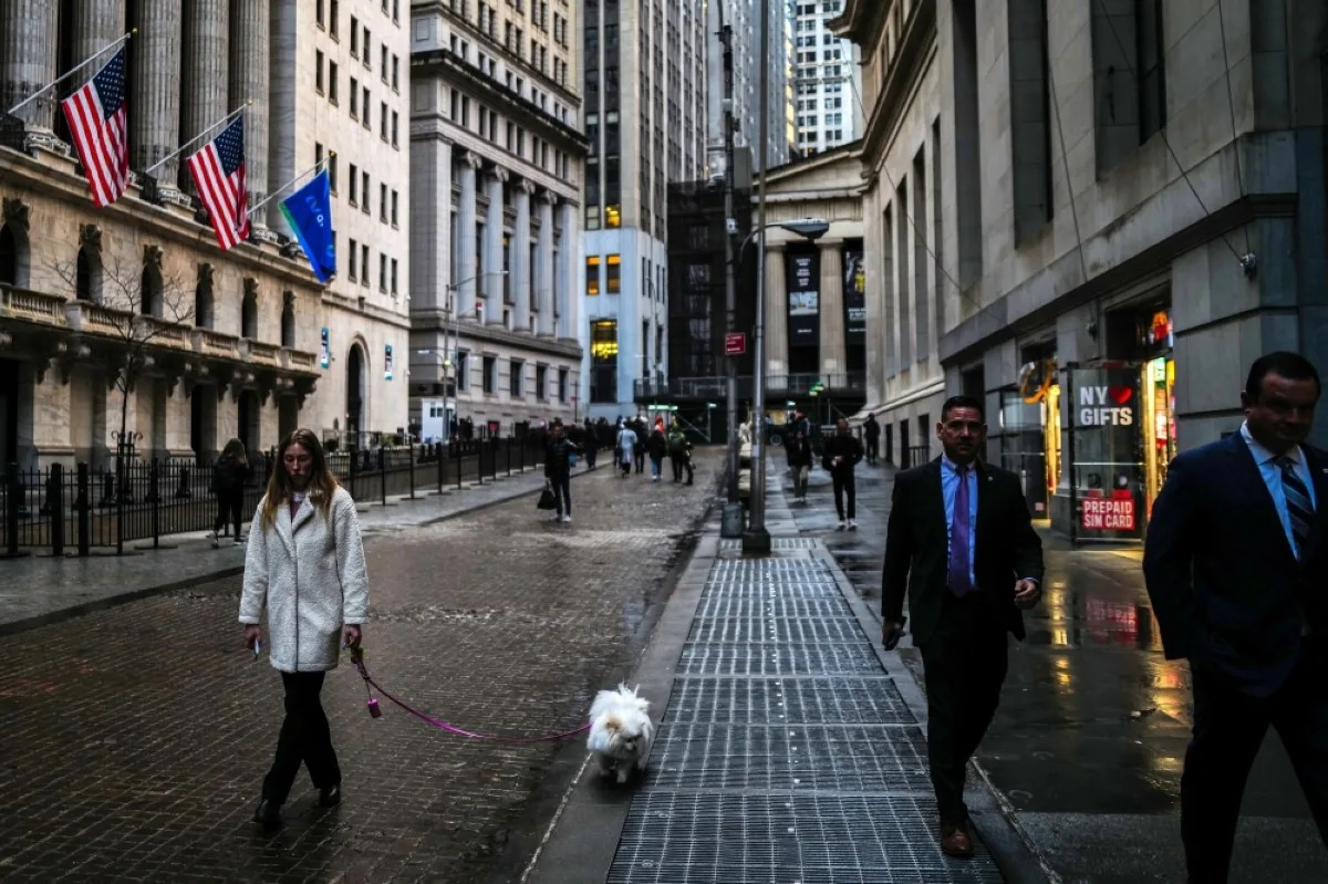 NEW YORK: A woman walks her dog past the New York Stock Exchange (NYSE) (left) at Wall Street in the Manhattan borough of New York.- AFP
