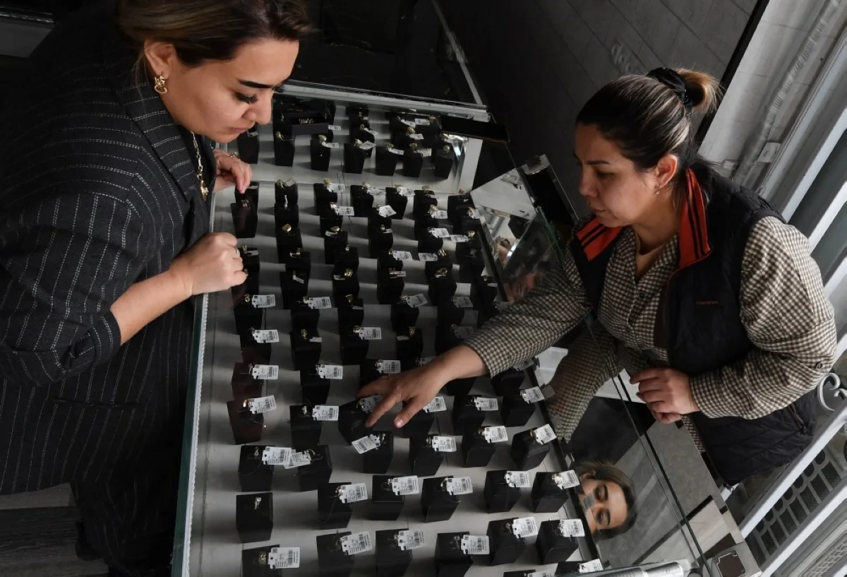 TASHKENT: A woman examines gold jewelry in a gold store in Navoiy, some 500km from Tashkent. -- AFP