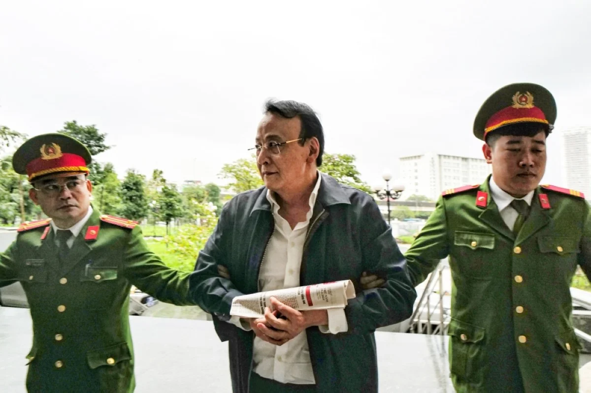 HANOI, Vietnam: Chairman of Tan Hoang Minh group Do Anh Dung (center) is escorted by police officers to a court for his trial on fraud charges in Hanoi. – AFP